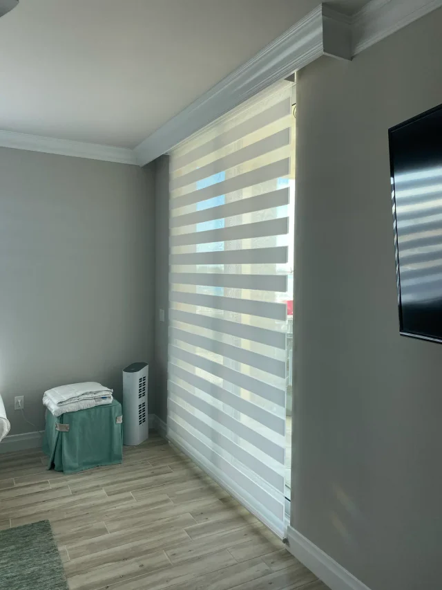 Layered shades with sheer and opaque bands across a glass door