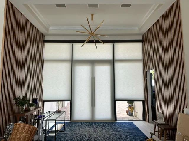 Roller shades across tall glass doors in a wood-paneled room