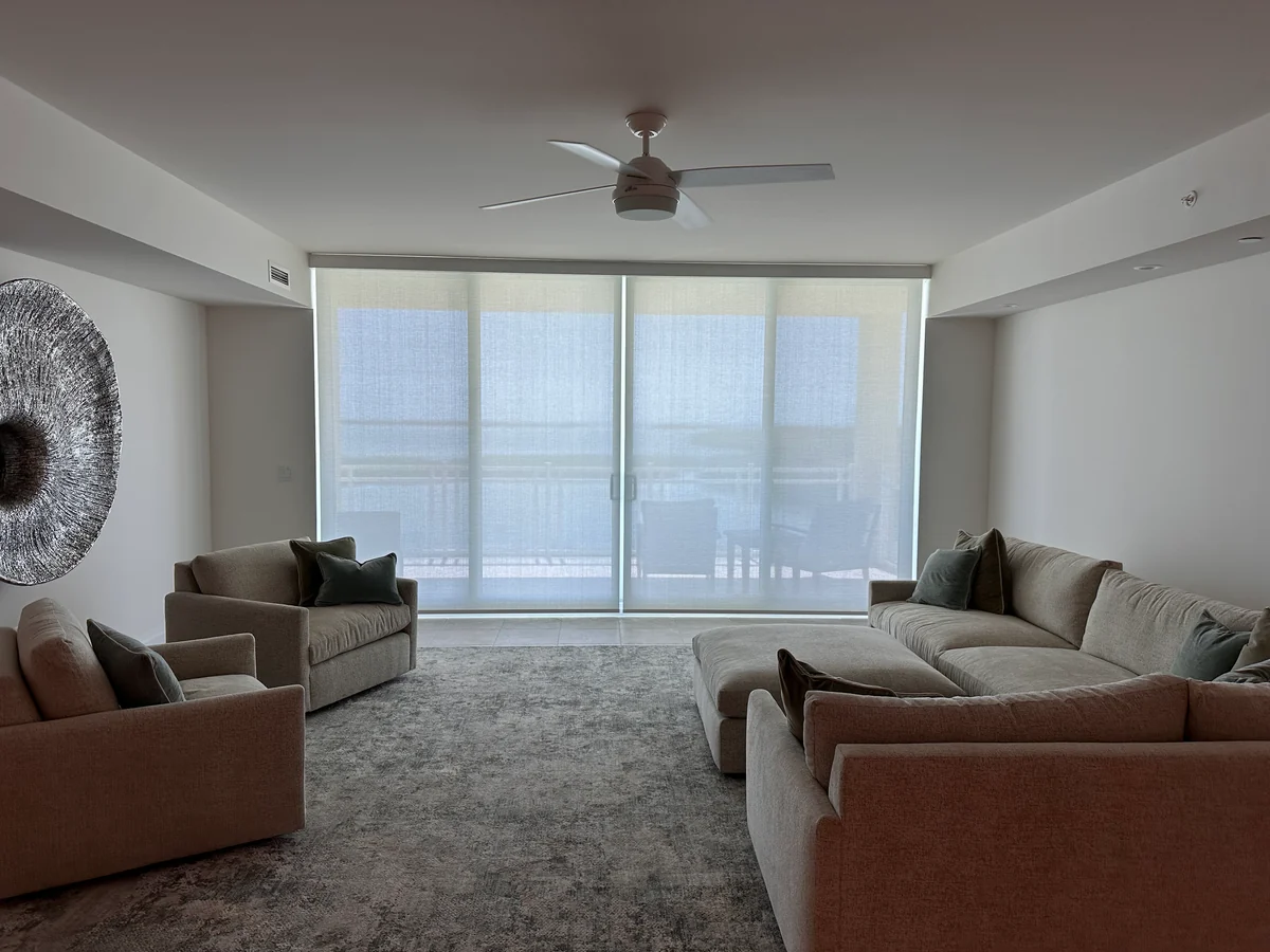 Light-filtering roller shades across sliding glass doors in a furnished living room