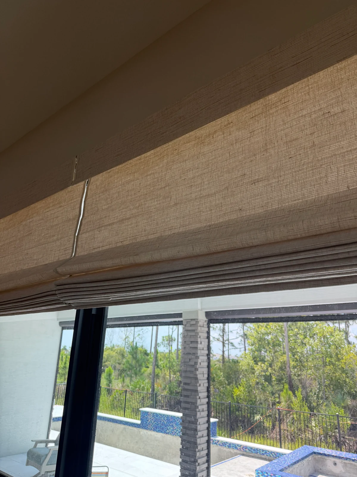 Natural-textured Roman shades partially raised into soft folds above patio doors