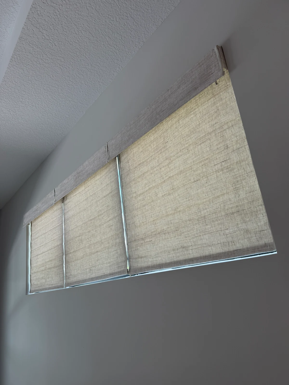 Three natural-textured Roman shades lowered across neighboring windows