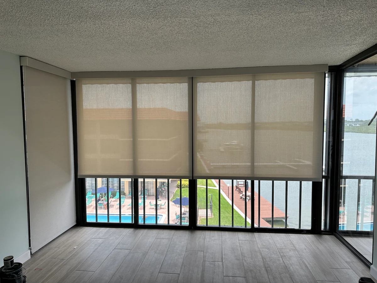 Solar shades lowered across sunroom windows overlooking a waterfront patio